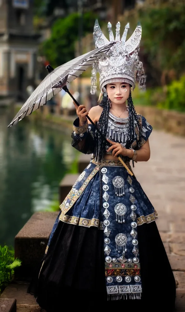 Miao-Frau mit gigantischem Silberkopfschmuck und Sonnenschirm