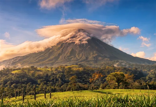 Vulkan Arenal in Costa Rica mit Wolken und grünem Vordergrund